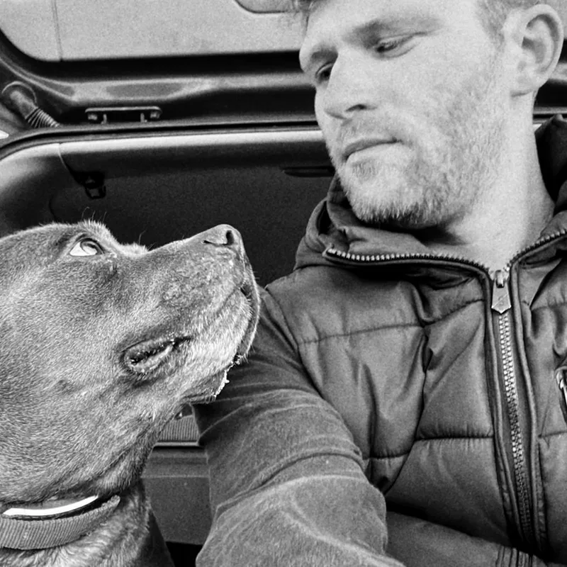 Dan and Alfie the dog looking at each other in the back of a car (black-and-white photo)